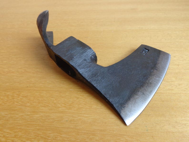 May include: A black metal axe with a curved handle and a sharp blade. The axe has a small, rectangular hole in the handle.
