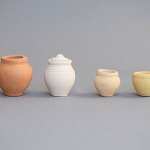 May include: Four small ceramic pots in different colours and sizes. The pots are arranged in a row from left to right. The pot on the left is brown, the next is white, the third is light brown, and the last is yellow.