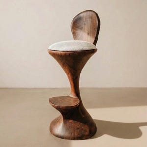 May include: A tall bar stool crafted from dark brown wood with a smooth, curved, hourglass-shaped base and a small footrest. The seat is topped with a thick, round, off-white textured cushion, and the backrest is a solid, rounded piece of wood.