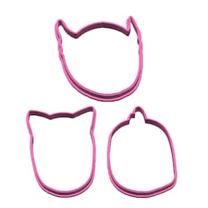 May include: Three pink plastic cookie cutters shaped like a monster, a cat, and a pumpkin.