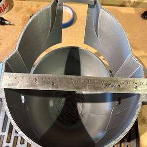 May include: A gray 3D printed helmet with a ruler measuring 21 inches across the inside of the helmet.