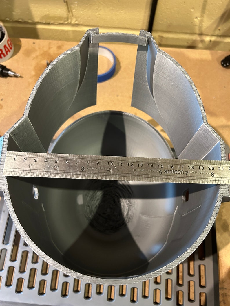 May include: A gray 3D printed helmet with a ruler measuring 21 inches across the inside of the helmet.