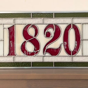 May include: A stained glass window with a white background and a green border. The number 1820 is displayed in red.