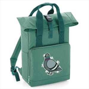 May include: Green backpack with a roll-top closure, a top handle, and adjustable shoulder straps. The front features a graphic of a pigeon. The backpack has a front zipped pocket and a buckle closure.