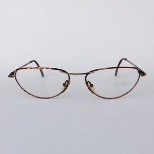 Op de afbeelding: Een bril met schildpadpatroon, een gouden metalen frame en heldere glazen. De merknaam "ANONIMO" staat op het rechterglas gedrukt.