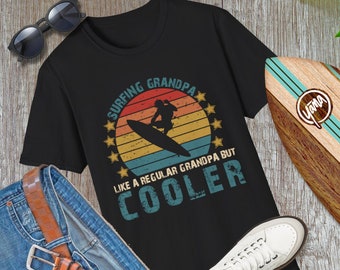 Può includere: Maglietta nera con una grafica in stile vintage di un surfista che cavalca un'onda. La grafica include il testo "Surfing Grandpa Like a Regular Grandpa But Cooler".