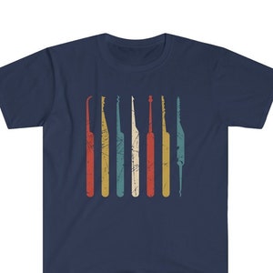 May include: A navy blue t-shirt featuring a vintage-style graphic of seven lock picks in red, yellow, blue, and green colours.