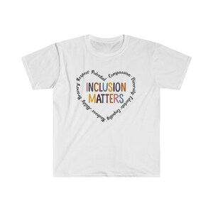 May include: White t-shirt with a circle graphic that says "Inclusion Matters" in colorful letters. The circle is surrounded by the words "Respect, Potential, Compassion, Diversity, Educate, Empathy, Kindness, Ability, Bravery."