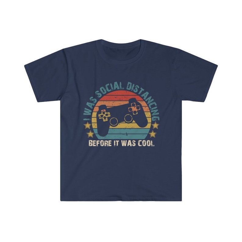 May include: Navy blue t-shirt with a retro-style graphic of a video game controller and the text "I was social distancing before it was cool."
