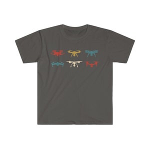 May include: Dark gray t-shirt featuring six drone illustrations in red, yellow, teal, blue, white, and orange. The drones are arranged in two rows of three. The shirt is a crew neck style.