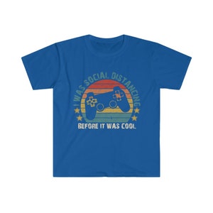 May include: A royal blue t-shirt with a vintage-style graphic of a video game controller and the text "I was social distancing before it was cool."
