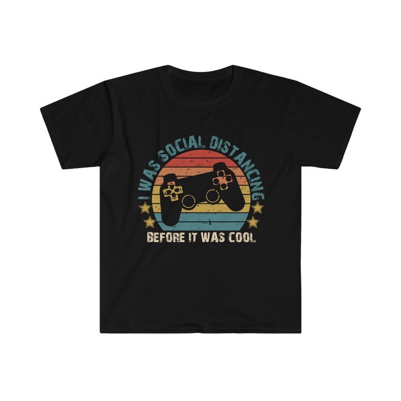 May include: Black t-shirt with a retro-style graphic of a video game controller and the text "I was social distancing before it was cool."