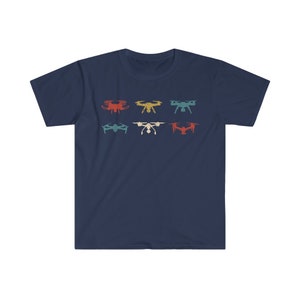 May include: Navy blue t-shirt featuring a retro design of six different drones in various colors. The drones are arranged in two rows of three, with colors including red, yellow, and teal. The shirt is made of a soft material.