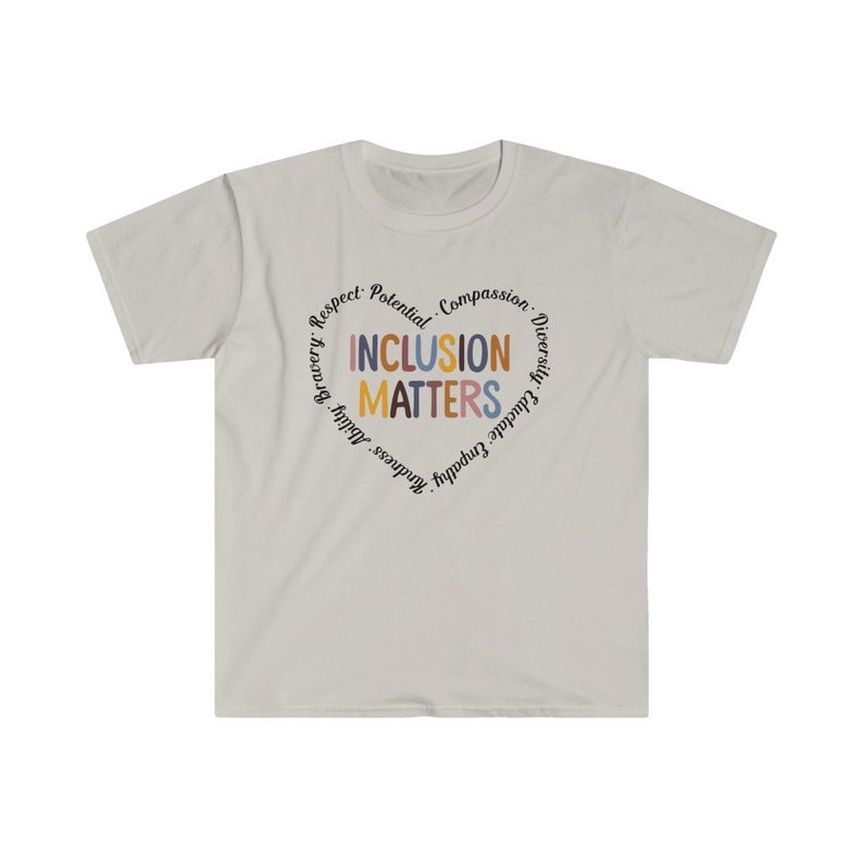 May include: A light gray t-shirt with a circular design featuring the words "Inclusion Matters" in colorful letters surrounded by a circle of words including "Respect, Potential, Compassion, Diversity, Empathy, Gratitude, Kindness, Bravery,  Adult,  Happiness".