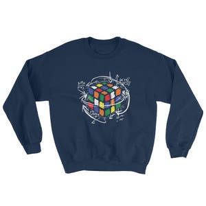 Puede incluir: Sudadera azul marino con un dise&ntilde;o blanco de un Cubo de Rubik rodeado de s&iacute;mbolos matem&aacute;ticos y flechas. El dise&ntilde;o del cubo presenta una variedad de colores, incluyendo rojo, azul, verde, amarillo y naranja.
