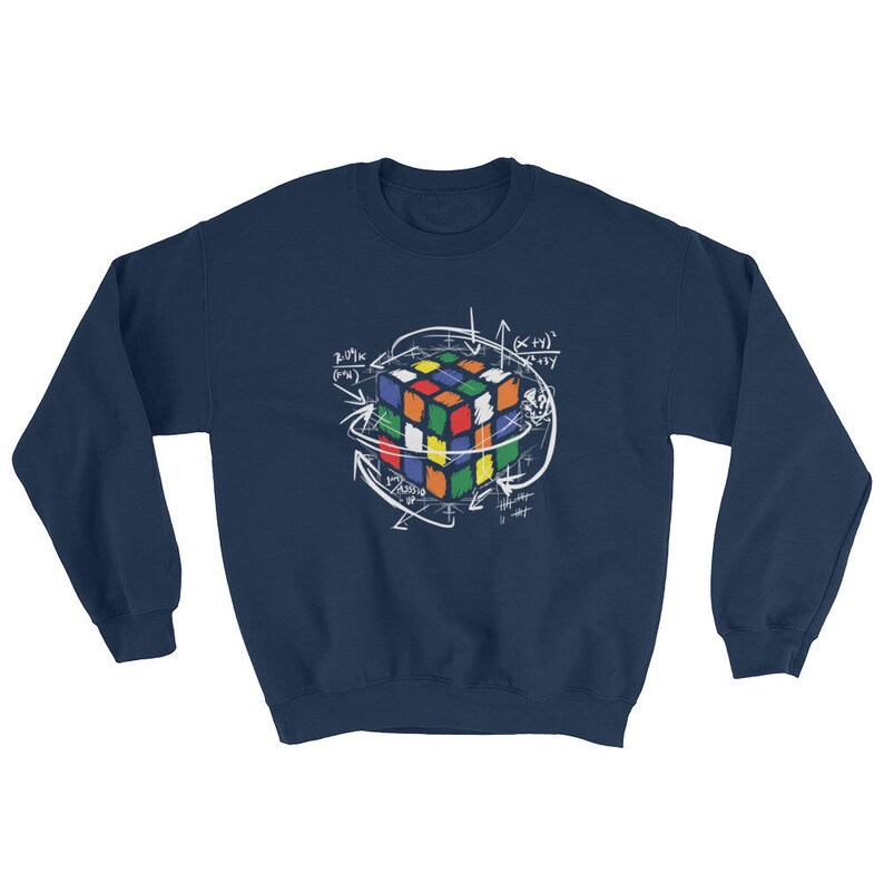 Puede incluir: Sudadera azul marino con un dise&ntilde;o blanco de un Cubo de Rubik rodeado de s&iacute;mbolos matem&aacute;ticos y flechas. El dise&ntilde;o del cubo presenta una variedad de colores, incluyendo rojo, azul, verde, amarillo y naranja.