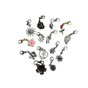 May include: Assortment of silver and gold tone metal charms featuring flowers, leaves, and a heart. The charms have a lobster claw clasp for attaching to a zipper pull, purse, or other item.