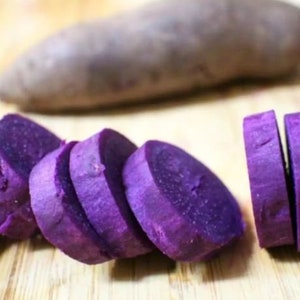 Puede incluir: Boniato morado cortado en rodajas. Las rodajas est&aacute;n dispuestas sobre una superficie de madera.