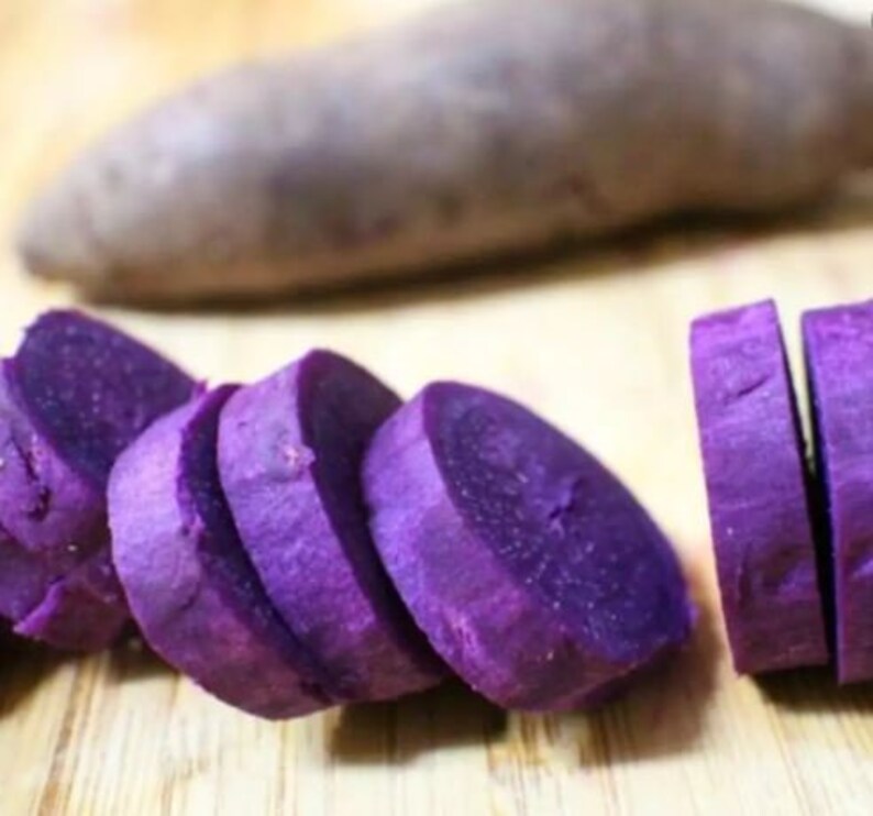 Puede incluir: Boniato morado cortado en rodajas. Las rodajas est&aacute;n dispuestas sobre una superficie de madera.