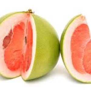 Pode incluir: Um pomelo cortado ao meio com polpa vermelha vibrante e uma casca espessa verde p&aacute;lido, ao lado de uma &uacute;nica fatia. O interior da fruta &eacute; suculento e segmentado, contrastando com o exterior liso. O fundo &eacute; branco liso.