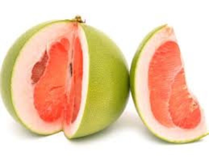 Pode incluir: Um pomelo cortado ao meio com polpa vermelha vibrante e uma casca espessa verde p&aacute;lido, ao lado de uma &uacute;nica fatia. O interior da fruta &eacute; suculento e segmentado, contrastando com o exterior liso. O fundo &eacute; branco liso.
