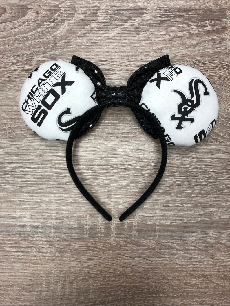 May include: Black headband with white fabric mouse ears featuring the Chicago White Sox logo. The ears are decorated with black sequins.