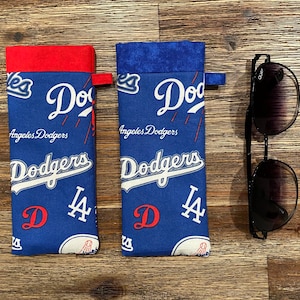 Könnte beinhalten: Zwei blaue und rote Stoffbeutel mit dem Logo der Los Angeles Dodgers und dem Text "Dodgers" und "LA".