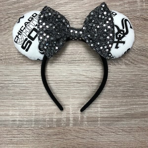 May include: Black headband with a white bow and two white fabric ears. The ears have the text "CHICAGO WHITE SOX" and a baseball logo on them.