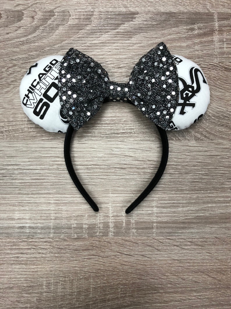 May include: Black headband with a white bow and two white fabric ears. The ears have the text "CHICAGO WHITE SOX" and a baseball logo on them.