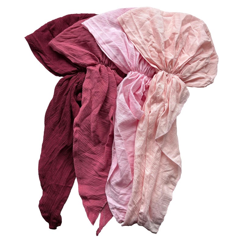 Puede incluir: Cuatro pa&ntilde;uelos para la cabeza de tela en tonos burdeos, rosa y melocot&oacute;n. Los pa&ntilde;uelos est&aacute;n hechos de un material texturizado y est&aacute;n recogidos en la parte superior. Los pa&ntilde;uelos est&aacute;n dispuestos en forma de abanico.