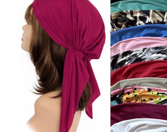May include: A magenta head wrap with a gathered side detail and two long fabric ties hanging down. The head wrap is shown on a mannequin head, with a vertical column of various other colors and patterns of the same head wrap style displayed.