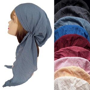 Puede incluir: Un pa&ntilde;uelo azul con un dise&ntilde;o plisado, atado en la parte posterior, se muestra en una cabeza de maniqu&iacute;. Tambi&eacute;n se ven otros pa&ntilde;uelos en varios colores, incluyendo negro, azul, rojo, rosa y beige.