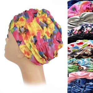 May include: A colorful floral print satin bonnet in shades of pink, yellow, and blue. The bonnet is gathered at the top and has an elastic band. A variety of other bonnets are visible in the background.