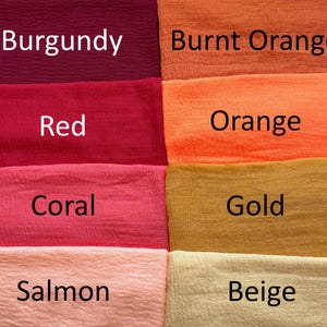 Op de afbeelding: Een raster van acht gestructureerde stofstalen in verschillende kleuren, elk gelabeld met de bijbehorende naam: Burgundy, Burnt Orange, Red, Orange, Coral, Gold, Salmon en Beige. De stof heeft een gekreukeld, gaasachtig uiterlijk.