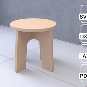 Puede incluir: Un pequeño taburete de madera de color claro con un asiento redondo y tres patas. Las patas están conectadas por un soporte curvo. El taburete está diseñado para uso en interiores. La imagen también incluye iconos de tipo de archivo: SVG, DXF, AI y PDF.