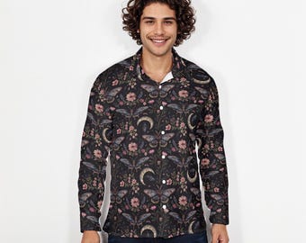 Pode incluir: Camisa de manga comprida com fundo escuro com um padrão floral e de borboletas em tons de rosa, cinza e branco. A camisa tem uma gola clássica e é usada com jeans azuis.