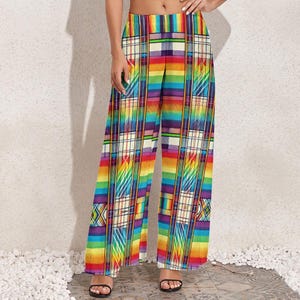 May include: Wide-leg pants with a vibrant rainbow plaid pattern. The design incorporates stripes and geometric shapes in a spectrum of colors, including red, orange, yellow, green, blue, and purple. The pants have a high waist and a flowing silhouette.