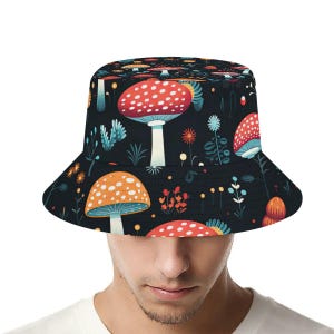 May include: A black bucket hat with a colorful mushroom print. The mushrooms are red, orange, yellow, and white with black spots. The hat has a wide brim and a flat crown.