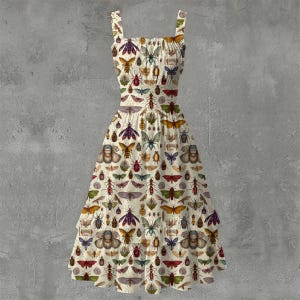 Puede incluir: Un vestido de verano color crema con un estampado de varios insectos en tonos marrón, morado, verde y naranja. El vestido tiene un escote cuadrado, tirantes ajustables y una falda escalonada. El diseño general es de inspiración vintage.
