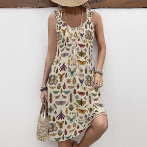 May include: A sleeveless, knee-length dress with a cream background and a repeating pattern of colorful insects. The dress has a scoop neckline and ruffled straps. The person is wearing a straw hat, beaded necklaces, and bracelets, and carrying a woven bag.