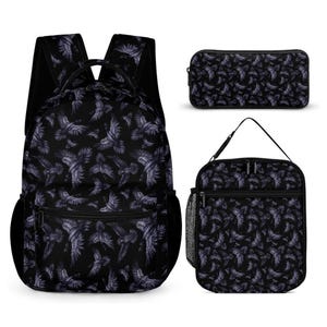 May include: A black backpack, a rectangular pencil case, and a square lunch bag, all featuring a repeating pattern of flying ravens in shades of purple and grey. The backpack includes shoulder straps, a top handle, and side mesh pockets.
