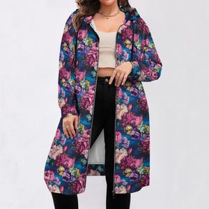 Puede incluir: Una chaqueta larga con capucha con un vibrante estampado floral en tonos rosa, morado y amarillo sobre un fondo azul oscuro. La chaqueta tiene una cremallera de largo completo y un forro interior blanco. Las mangas son largas y la chaqueta llega hasta las rodillas.