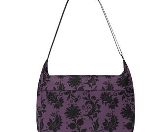 Könnte beinhalten: Eine violette Umhängetasche mit einem schwarzen Blumenmuster. Die Tasche hat einen langen verstellbaren Riemen.