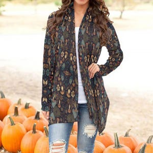May include: A long-sleeved cardigan with a dark background and a colorful mushroom and floral print. The cardigan is open in the front and has a relaxed fit.