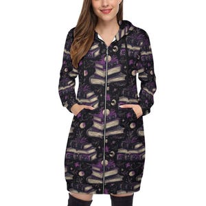 Peut inclure: Un long sweat à capuche noir zippé avec un motif répété de livres empilés, de lunes et d'étoiles en violet et crème. Le sweat à capuche a une capuche, des poches et une fermeture éclair sur toute la longueur. Thème mystique ou fantastique.