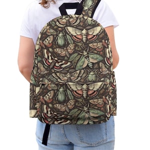 May include: A dark brown backpack featuring an all-over print of various moths, beetles, and green leaves. The bag includes a large main compartment, a front zippered pocket, and black shoulder straps, showcasing a detailed entomological pattern.