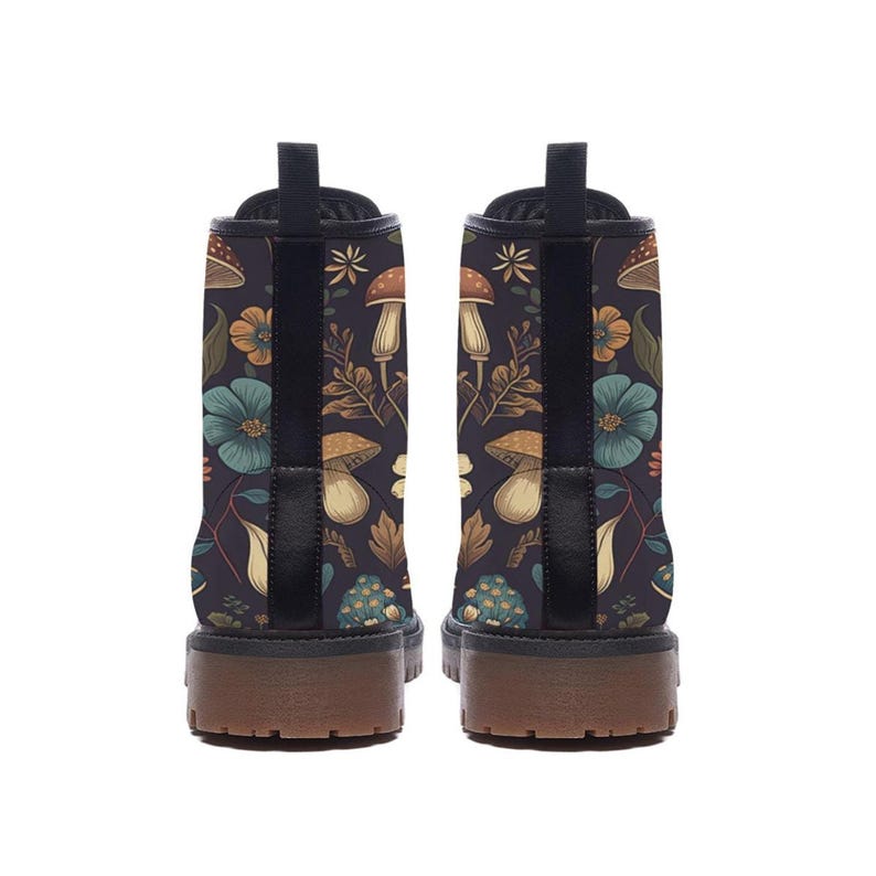 The back view of two black ankle boots showcasing their chunky brown lug soles and the continuous mushroom and flower pattern.