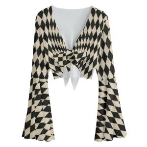 May include: A long-sleeved crop top featuring a black and cream diamond harlequin pattern. The garment has a deep V-neckline and a front tie closure that creates a gathered effect at the centre. The sleeves are flared, widening towards the wrists.