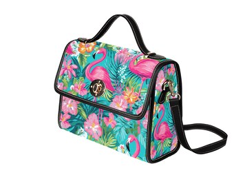 May include: A handbag with a tropical flamingo design. The bag features a teal background with pink flamingos, pink flowers, and green leaves. It has a black handle, black trim, and a black shoulder strap. The bag has a gold-colored clasp.