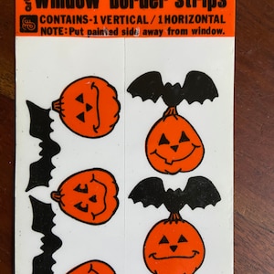 May include: A sheet of reusable, easy-cling window border strips featuring alternating black bats and orange pumpkins with jack-o-lantern faces. The package contains one vertical and one horizontal strip.  The text on the package reads "EASY-CLING window border strips REUSABLE CONTAINS-1 VERTICAL/1HORIZONTAL NOTE: Put painted side away from window."
